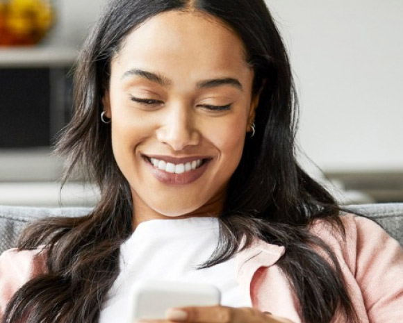 Suncorp Bank Shine Blog article: How to budget with the 70:20:10 rule – woman smiling using mobile phone