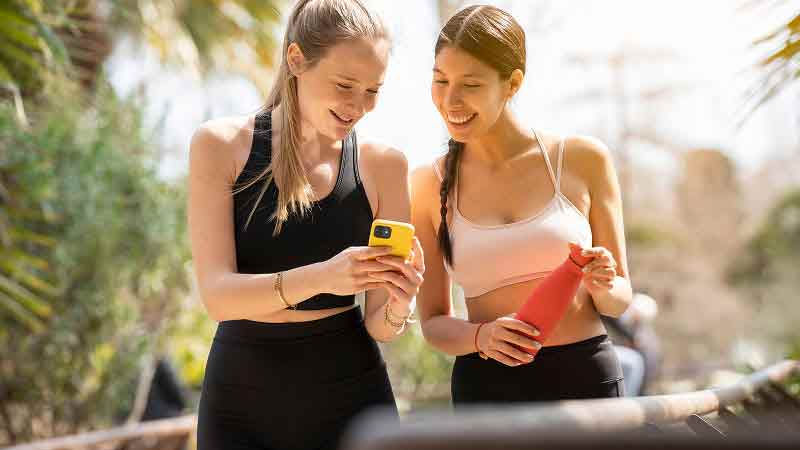 Two women walking outside and looking at a smartphone screen
