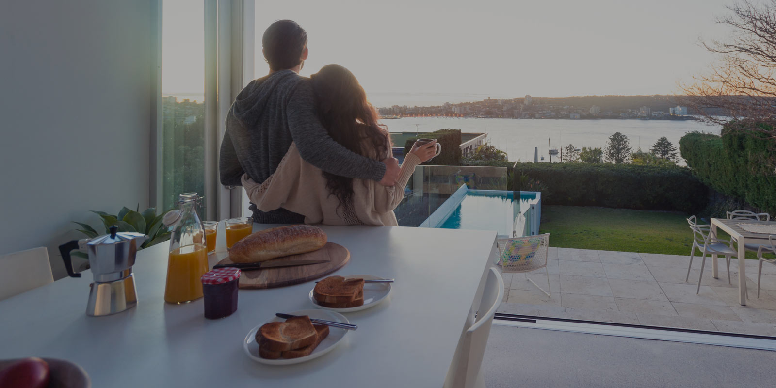 Couple hugging in kitchen overlooking water