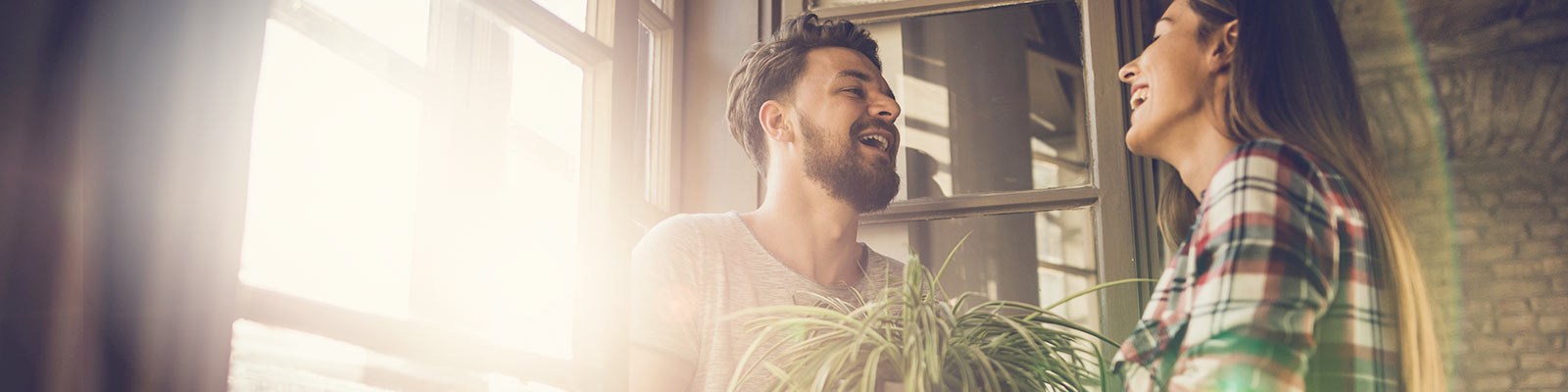 Acouple laughing & sitting at the bright sunny window.