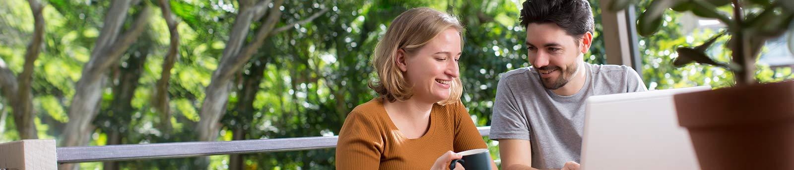 Young couple sitting on porch smiling and having coffee