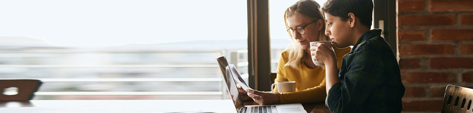 Two women looking at laptop and drinking coffee