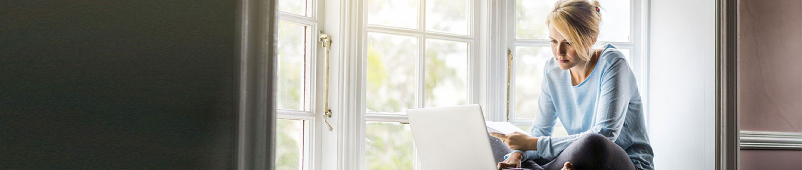 Woman with laptop sitting on windowsill