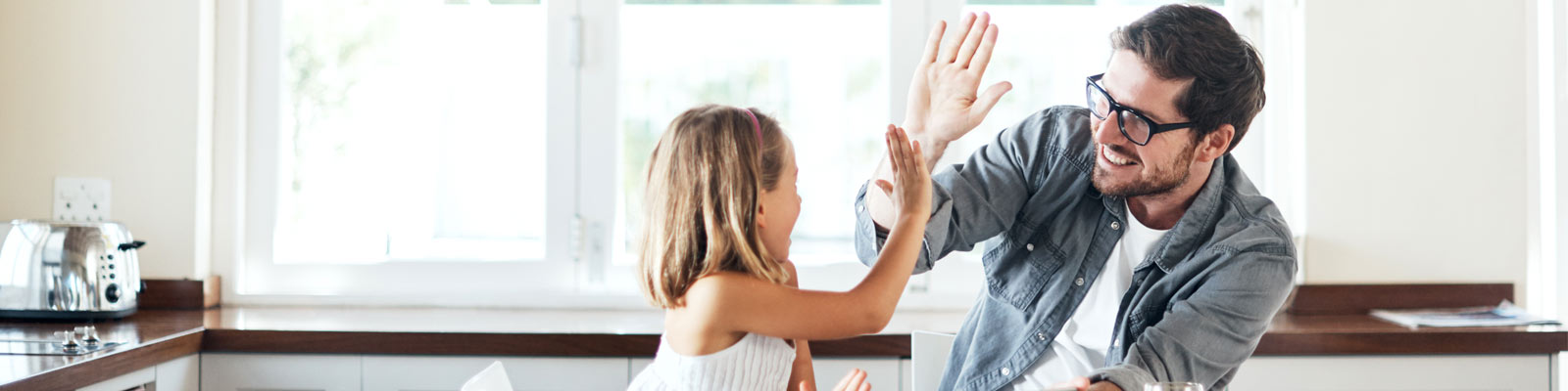 Father and daughter high five in kitchen