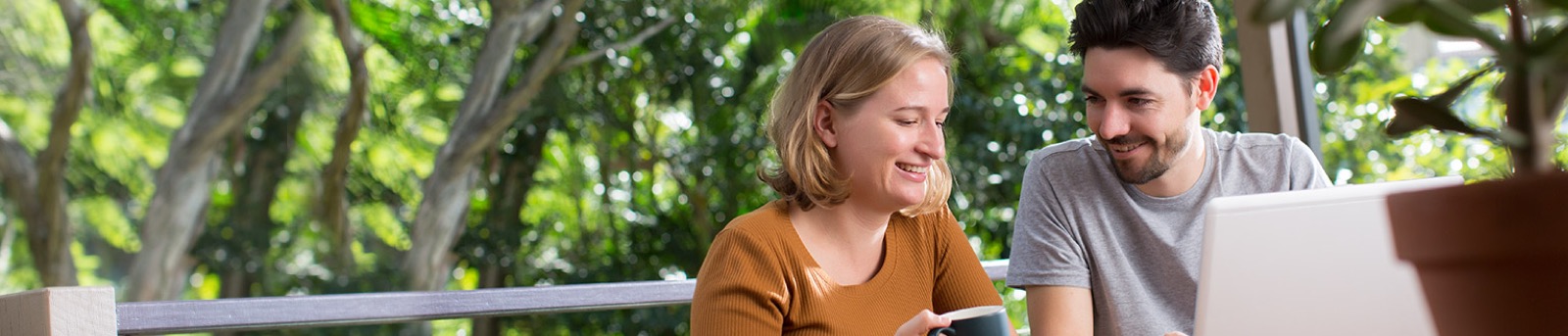 Young couple sitting on porch with laptop