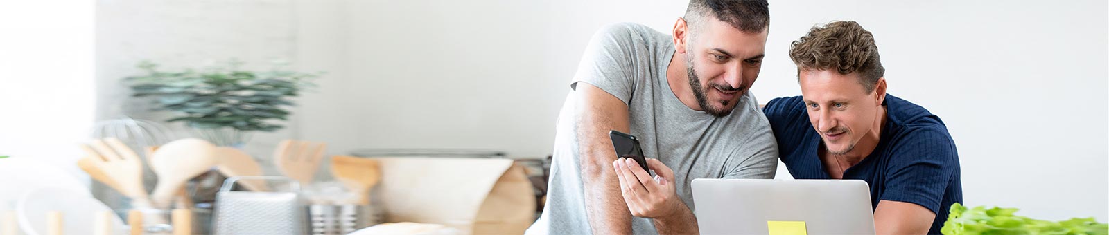 Two men looking at laptop and mobile phone