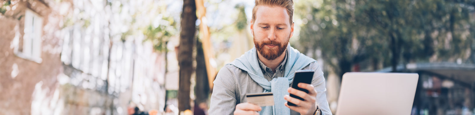 Man looking at card holding a smartphone