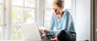 Woman with laptop sitting next to big window