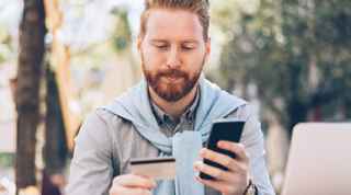 Man holding both a bank card and smartphone