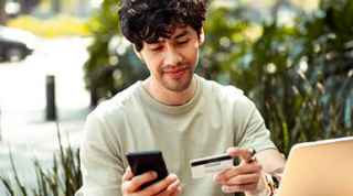 Man holding both a bank card and smartphone
