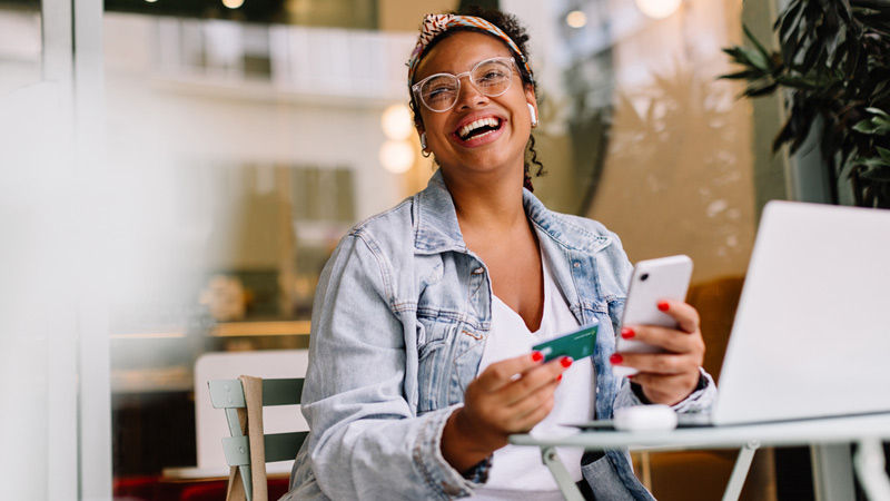 Woman smiling holding card and phone