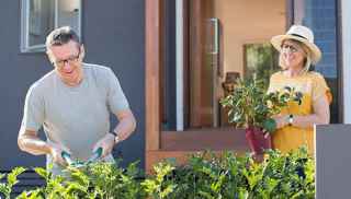 Man clipping the garden and woman holding a plant